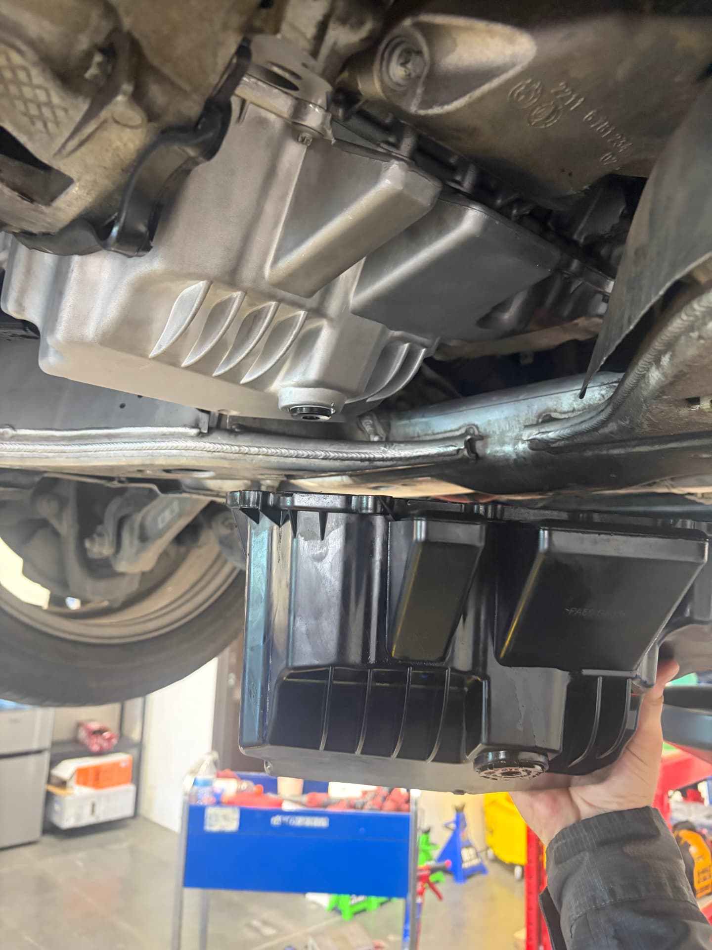 Technician removing the oil pan from a BMW on the lift at Johnny's Auto Repair on Ridgecrest Road in Victorville CA